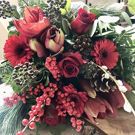 Christmas hand tied bouquet with fresh flowers in festive red tones with lush evergreens Christmas hand tied bouquet with fresh flowers in festive red tones with lush evergreens